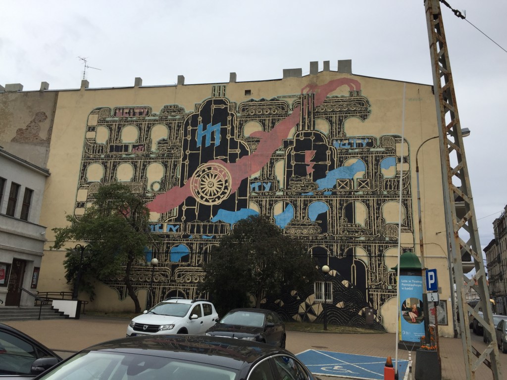 mural by mcity in Lodz looks like factory with train inside