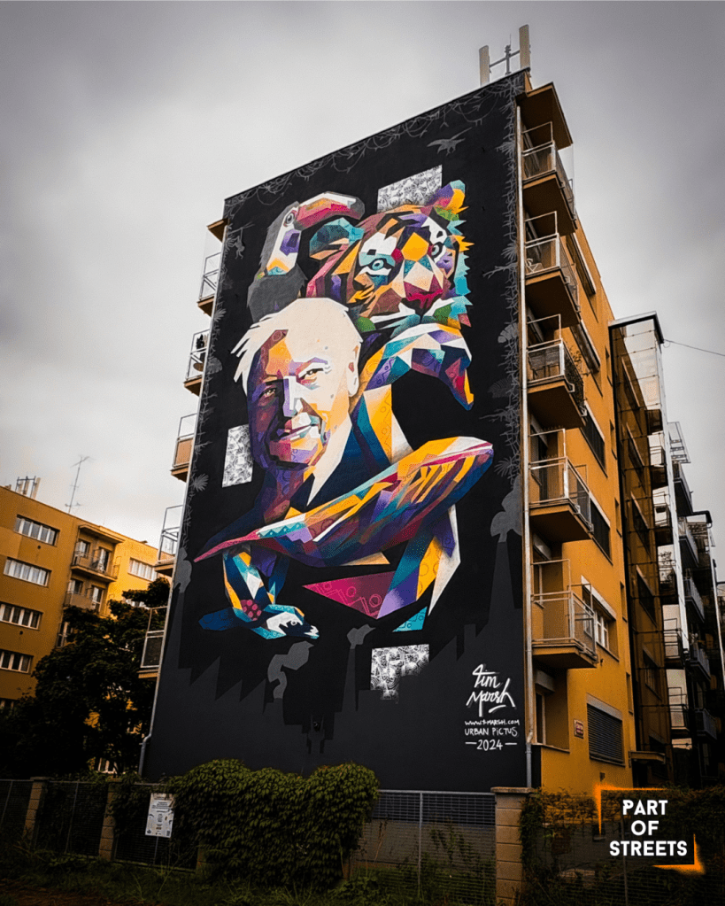 Colorful geometric mural of an older man and a tiger on the side of an apartment building in Prague.