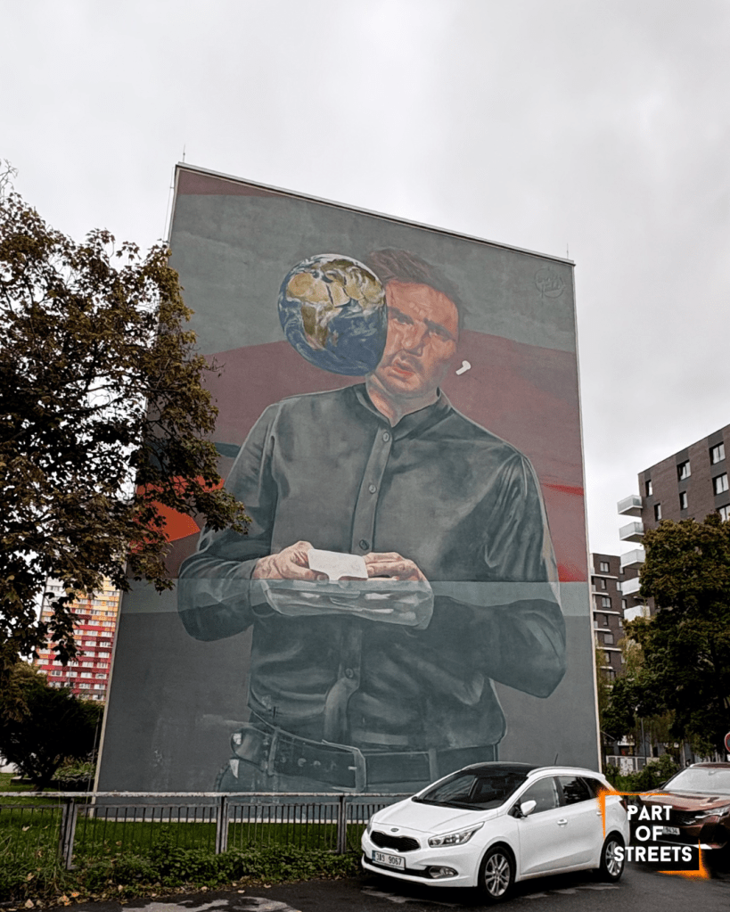 Large mural of a man holding a white phone with a floating Earth beside his face, painted on the side of a tall building.