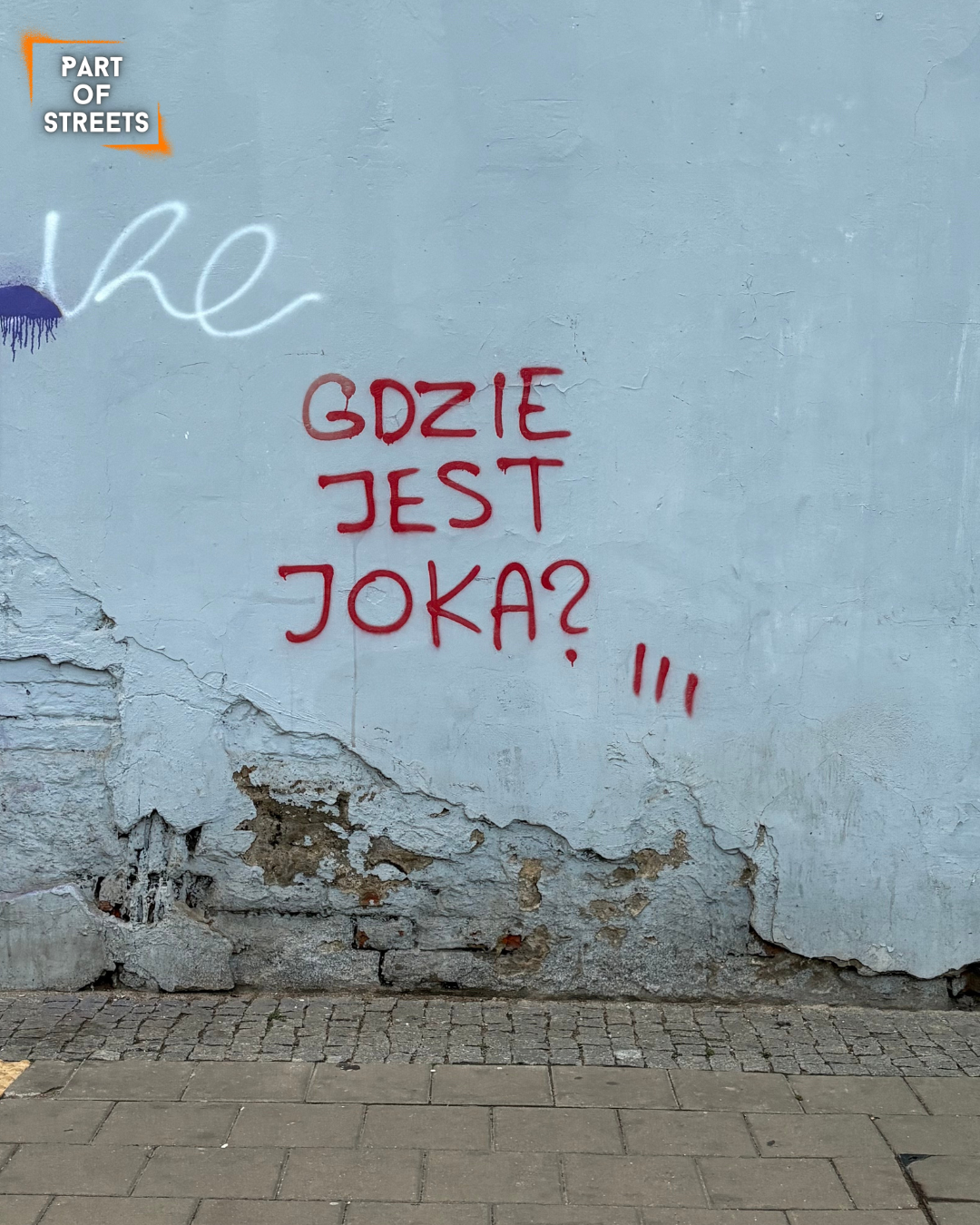 Red graffiti reading “GDZIE JEST JOKA?” (translated: “Where is Joka?”) sprayed on a cracked, pale blue wall with peeling paint and worn brick visible underneath. The text is written in capital letters.