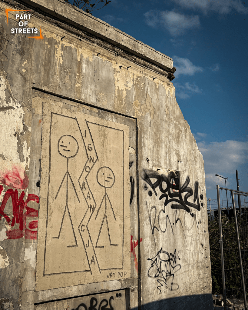 Łódź street art by JAY POP from the “Plasters” project, showing two stick figures with the word “Ignorancja” on a bricked-up wall.